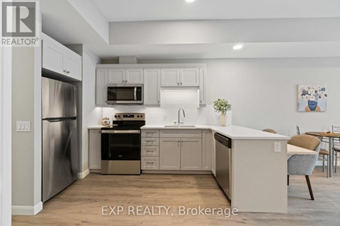 A kitchen with white cabinets and a stainless steel refrigerator.