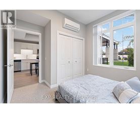 A bedroom with a large bed and a kitchen area in the background.