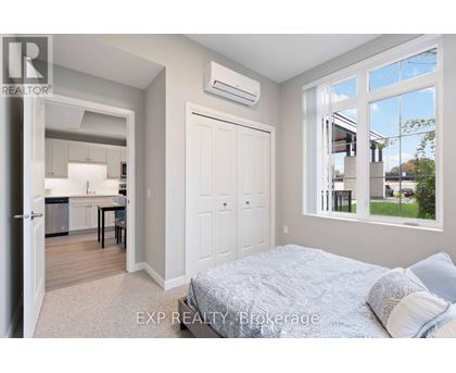 A bedroom with a large bed and a kitchen area in the background.