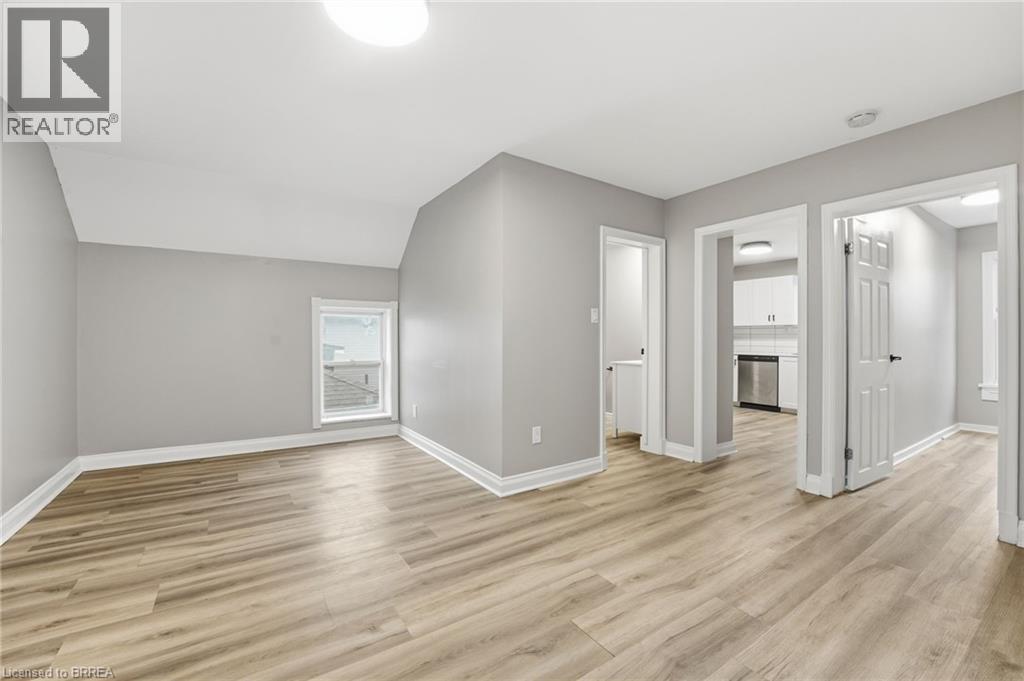 A spacious room with wooden flooring and white walls.