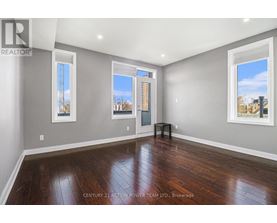 A spacious room with wooden floors and two windows.