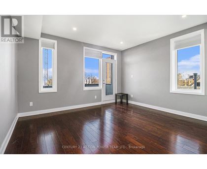 A spacious room with wooden floors and two windows.