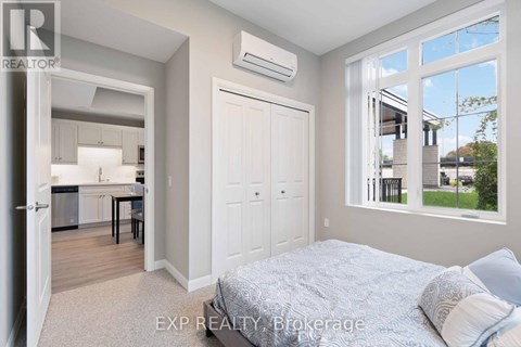 A bedroom with a large bed and a kitchen area in the background.