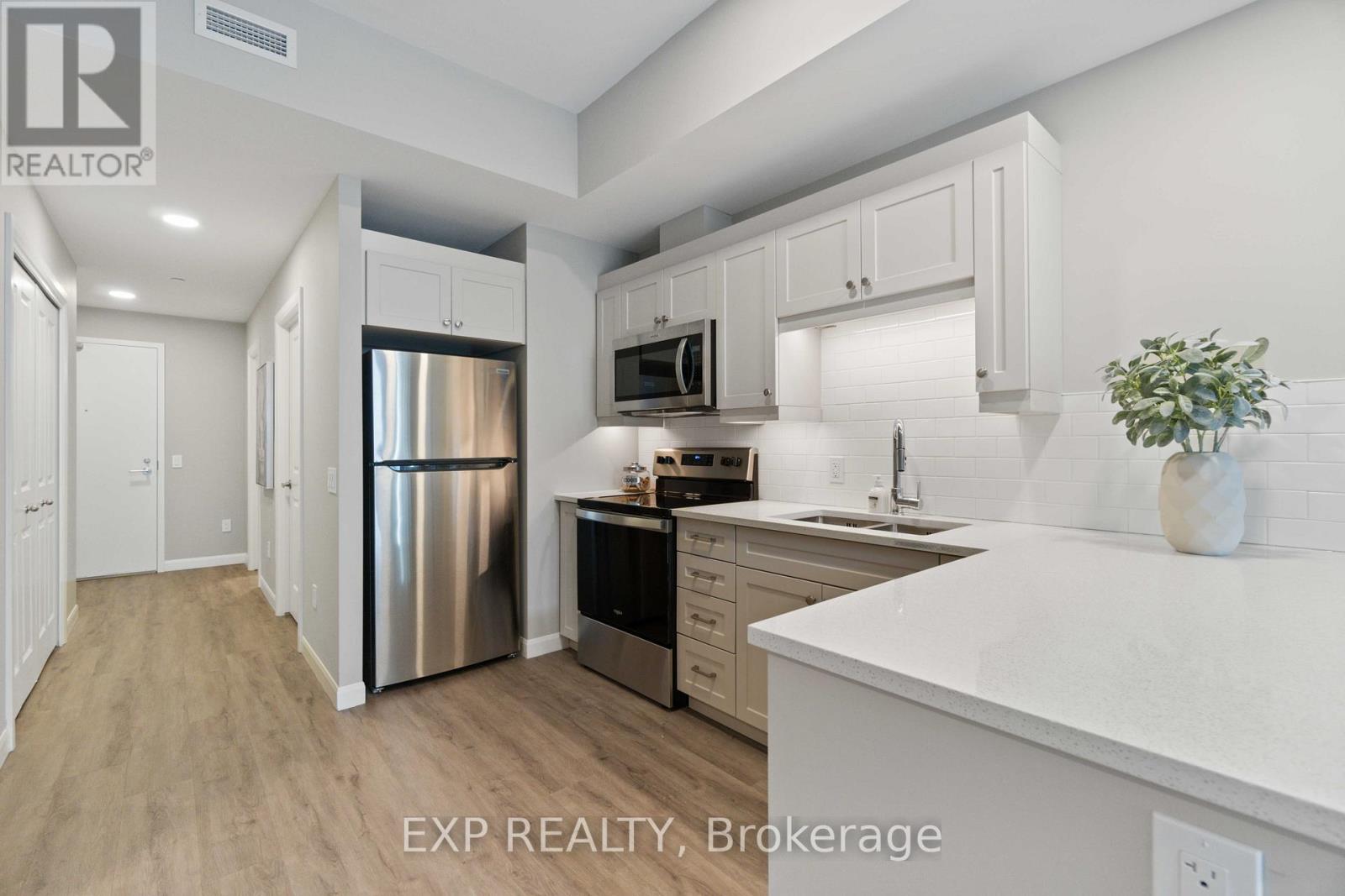 A kitchen with white cabinets and a stainless steel refrigerator.