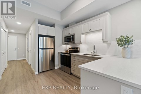 A kitchen with white cabinets and a stainless steel refrigerator.