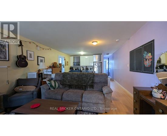 A living room with a grey couch and a guitar hanging on the wall.