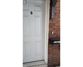 A white door with a mailbox on the side of a brick building.