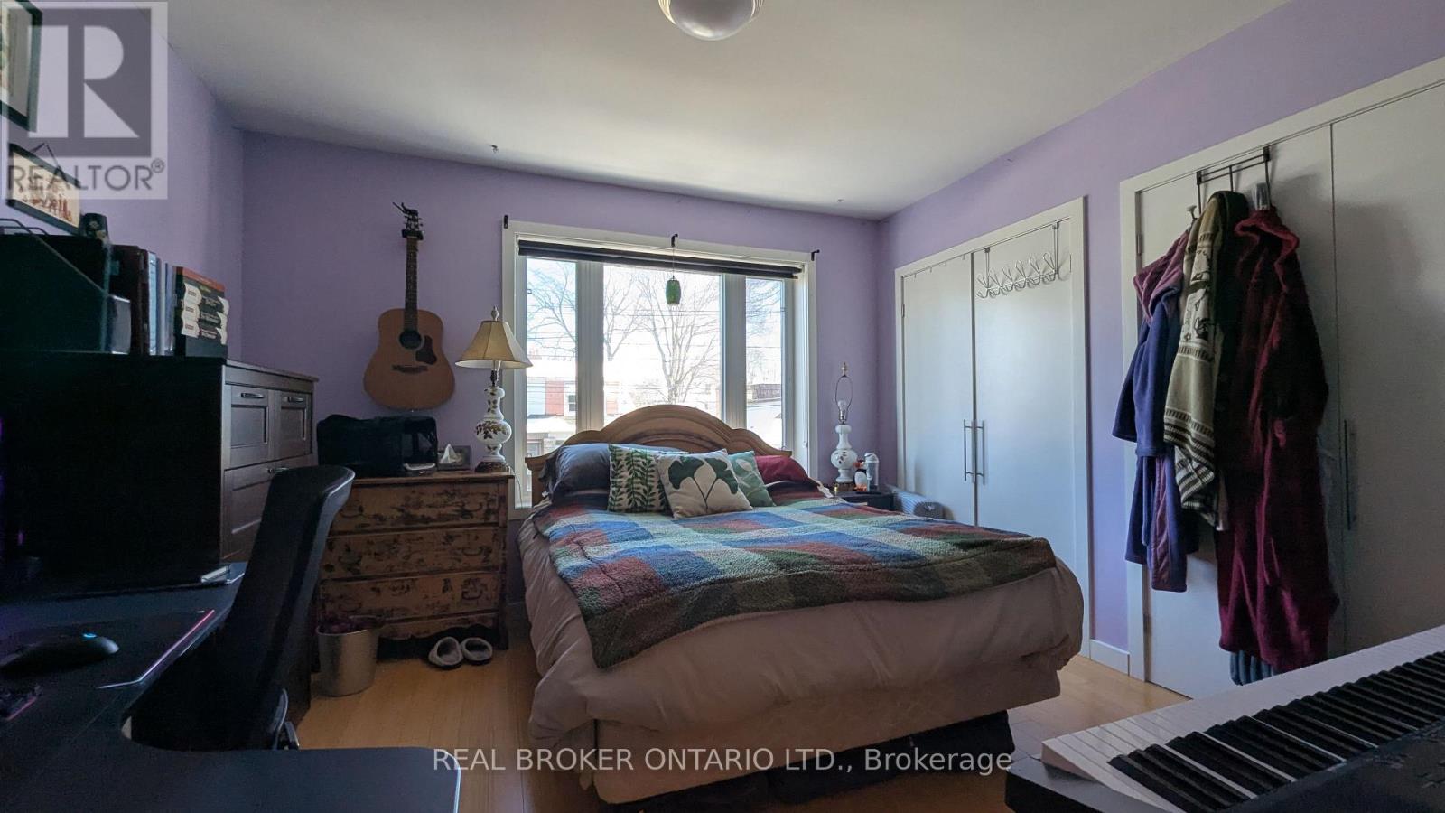 A bedroom with a bed, a guitar, a piano, and a window.