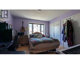 A bedroom with a bed, a guitar, a piano, and a window.