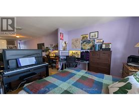 A bedroom with a bed, a piano, and a bookshelf.