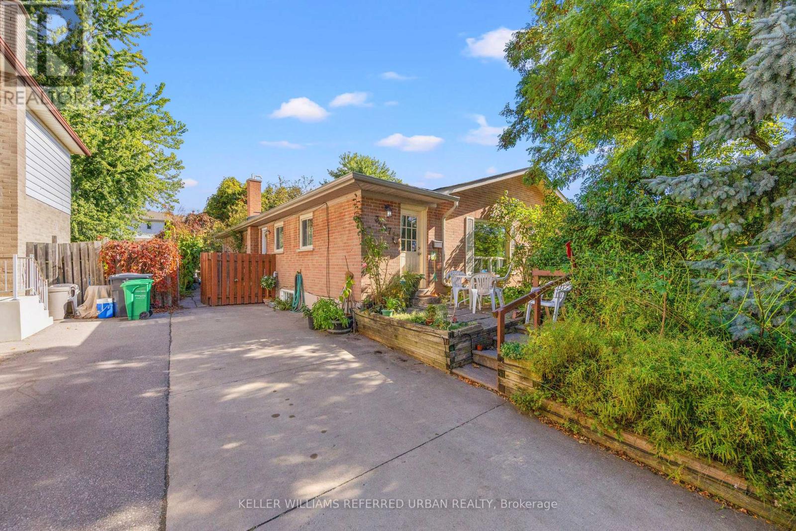 A house with a driveway and a green trash can.