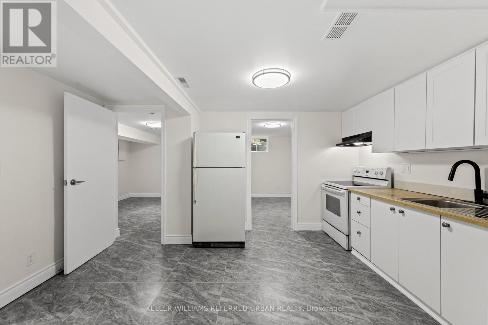 A kitchen with white cabinets and a marble floor.