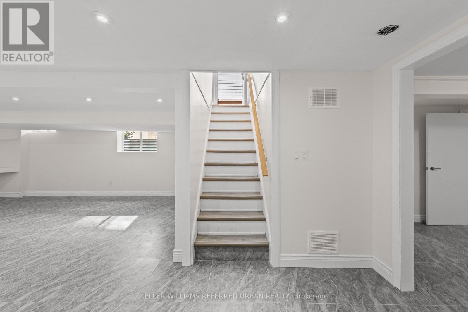 A spacious, empty room with a staircase leading to the upper floor.