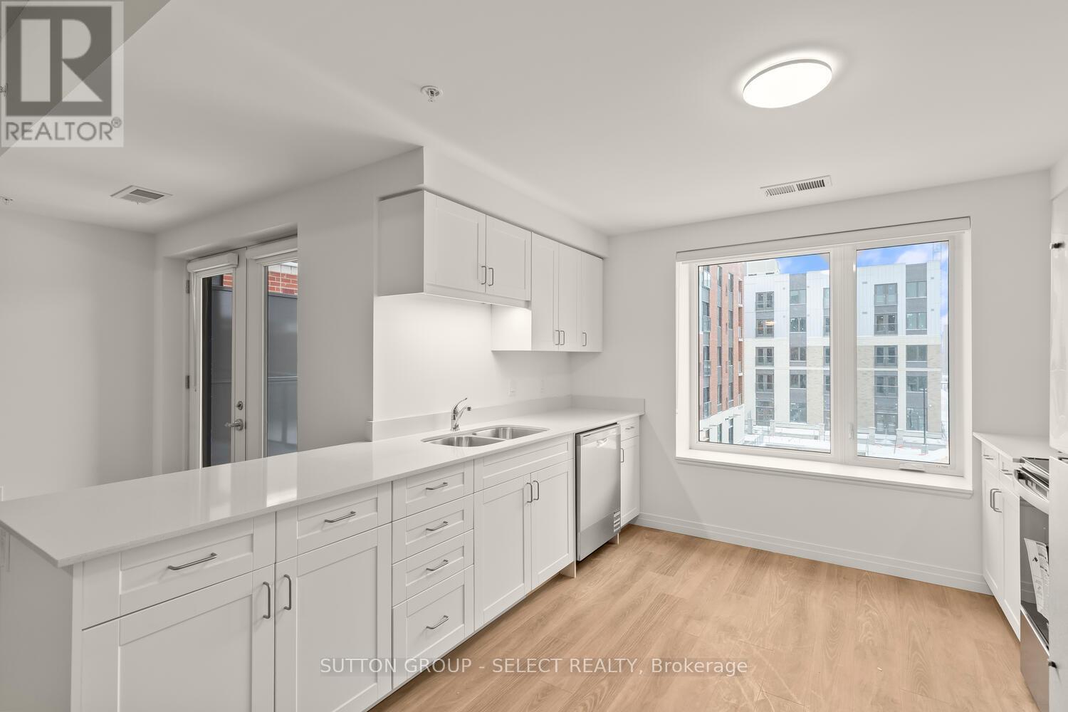 A modern kitchen with white cabinets and a window overlooking a cityscape.