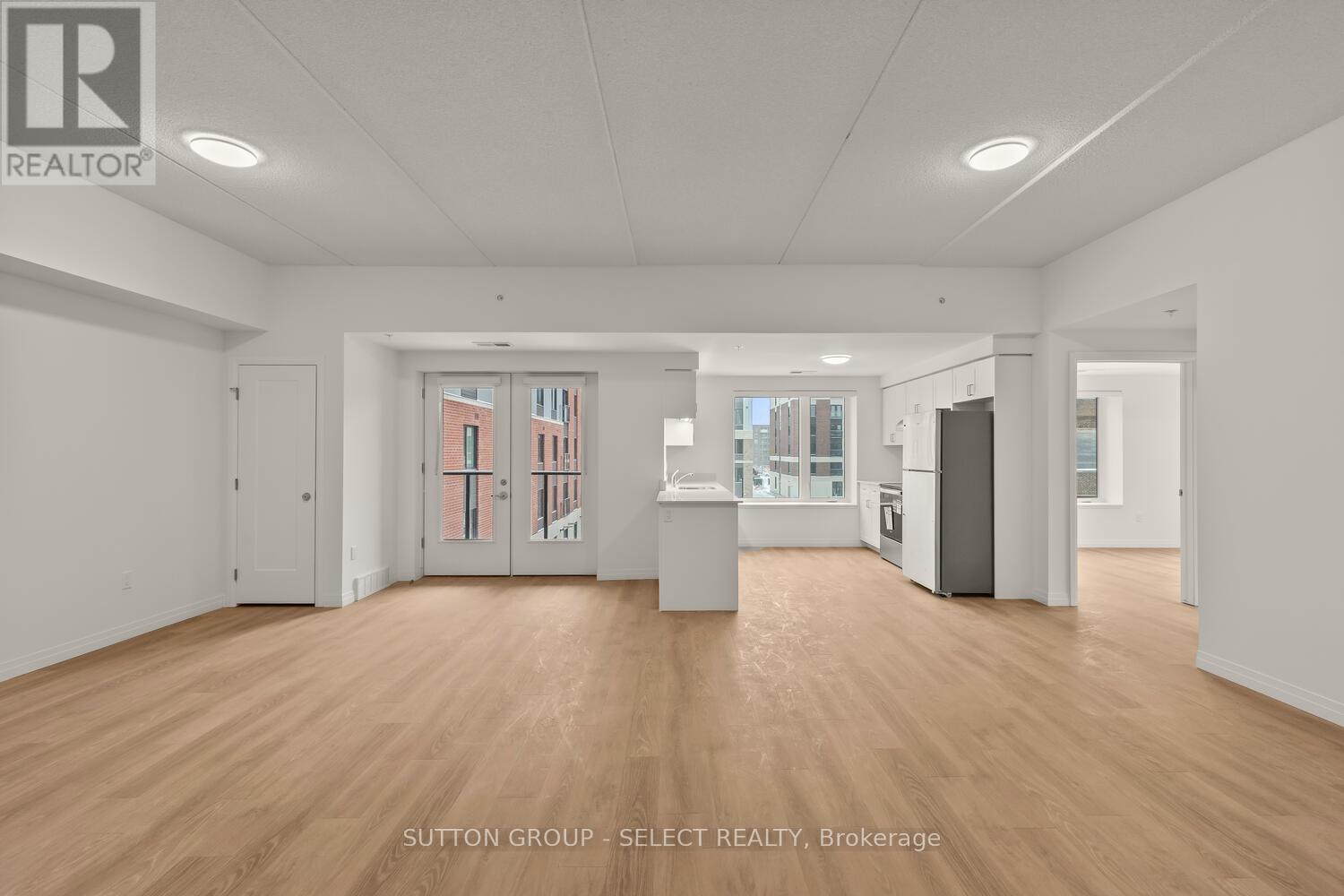 A spacious room with wooden floors and white walls, with a door leading to a balcony.