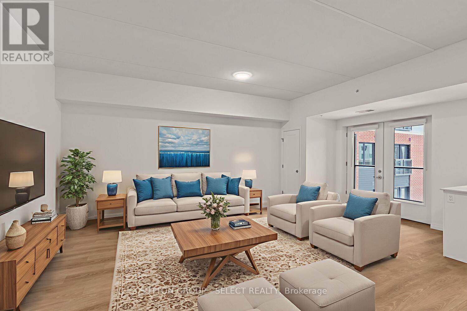 A living room with a white couch, blue pillows, and a painting on the wall.