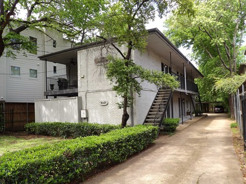 A white two-story apartment building with a black staircase.