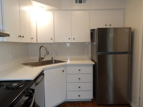 A kitchen with white cabinets and a stainless steel refrigerator.