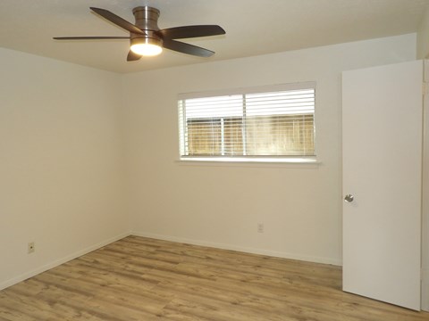A room with a ceiling fan and a window with blinds.
