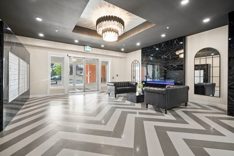 A spacious lobby with a large chandelier and a black and white checkered floor.