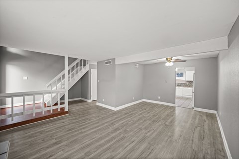 A spacious room with a staircase and a ceiling fan.