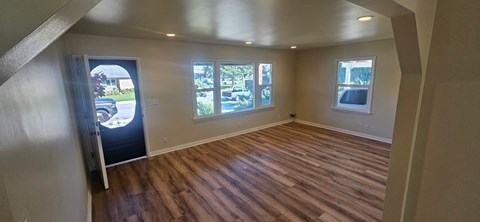 A room with wooden flooring and a door leading outside.