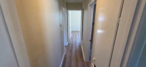 A long hallway with white walls and wood floors.