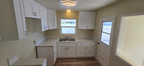 A kitchen with white cabinets and a window above the sink.