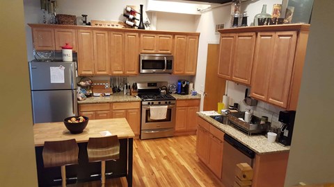 A kitchen with wooden cabinets and a stainless steel refrigerator.