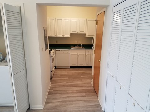 A kitchen with white cabinets and a wooden floor.