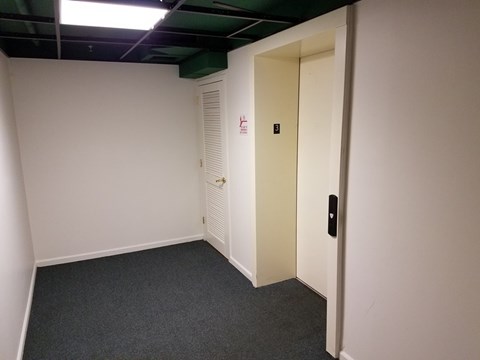 A white door with a black handle is on the right side of a room with a carpeted floor.