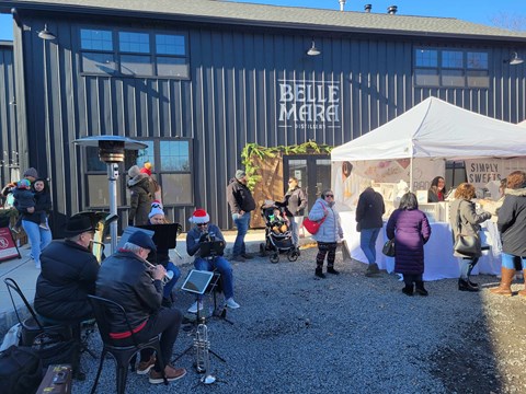 A group of people are gathered outside a building with the sign "Belle Mare" on it.