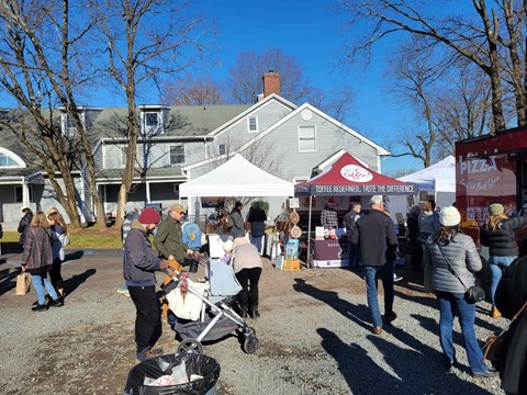 A group of people are walking around a white tent with a sign that says "Pizza".