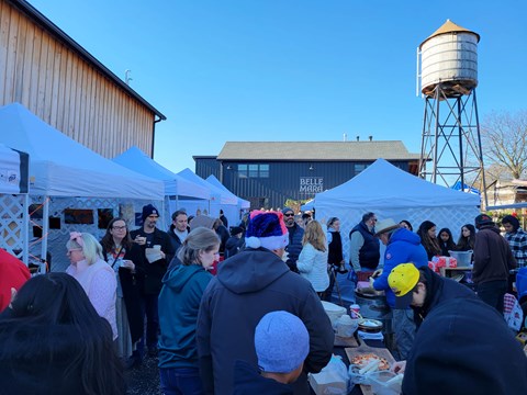 A group of people are gathered around a food stand at an outdoor event.