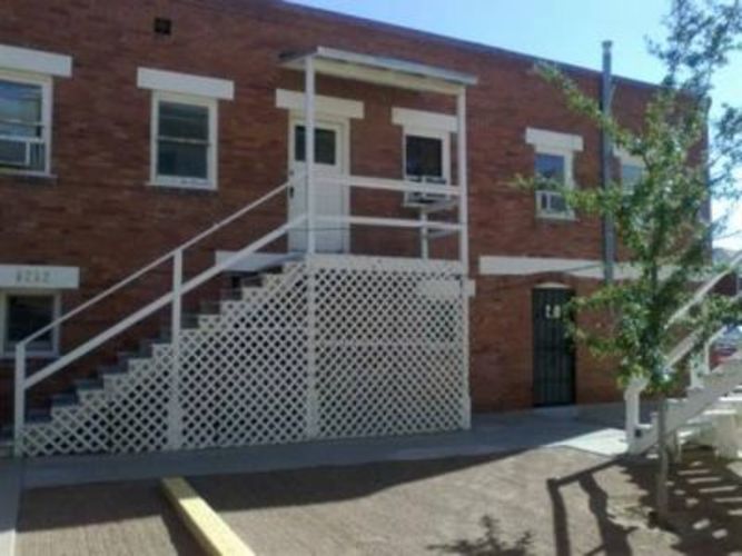 A red brick building with a white door and a white fence.