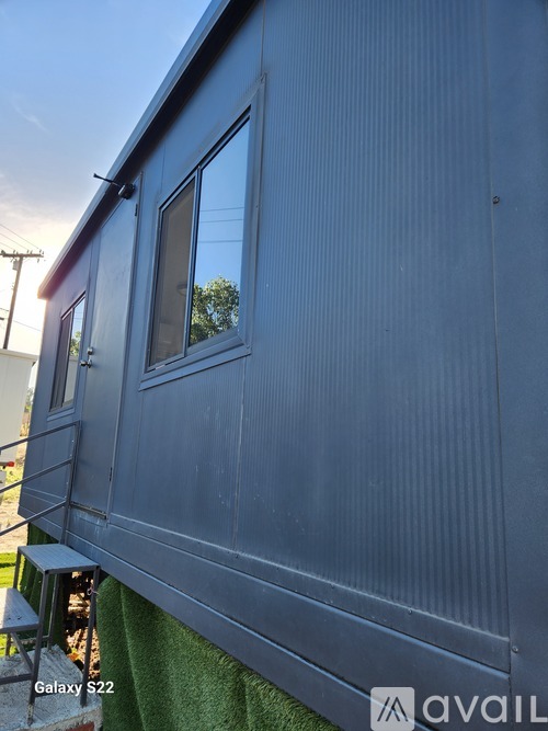 A blue trailer with a window and a door is parked.