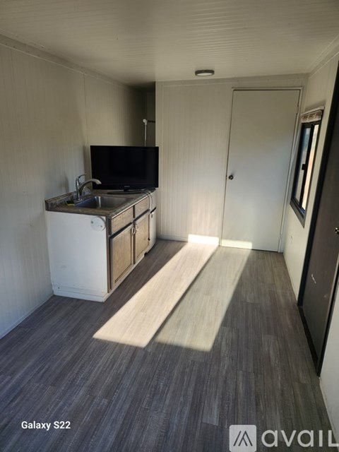 A small galley kitchen with a sink and a TV.