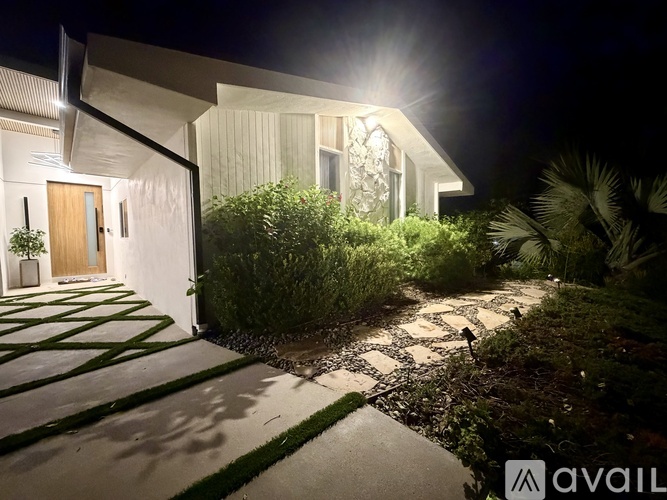 A house with a lit up window and a door is visible at night.