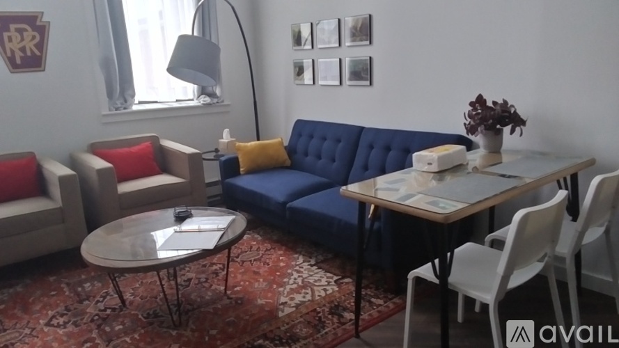 A living room with a blue sofa, a grey coffee table, and a white dining table with chairs.