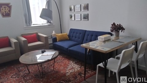 A living room with a blue sofa, a grey coffee table, and a white dining table with chairs.