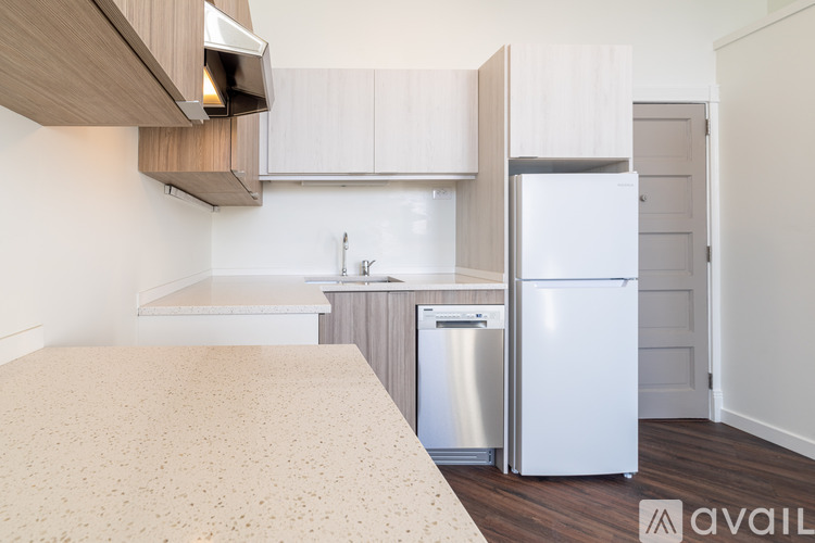 A kitchen with a refrigerator and a bed in a room.