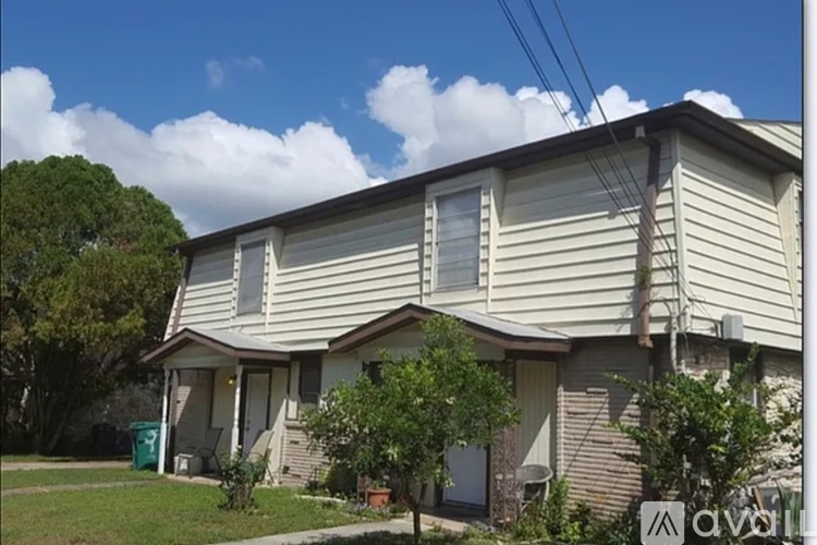 A house with a beige siding and a green trash can in front.