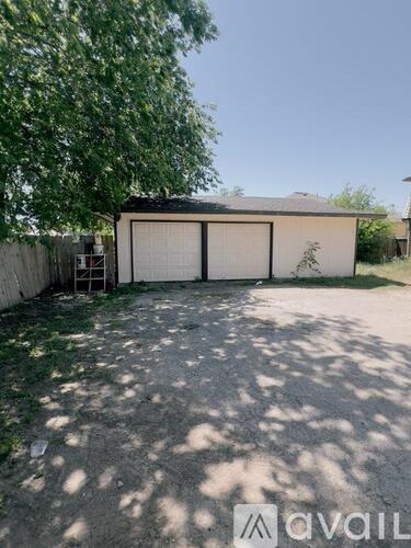 A small building with a white door is surrounded by a fence and trees.