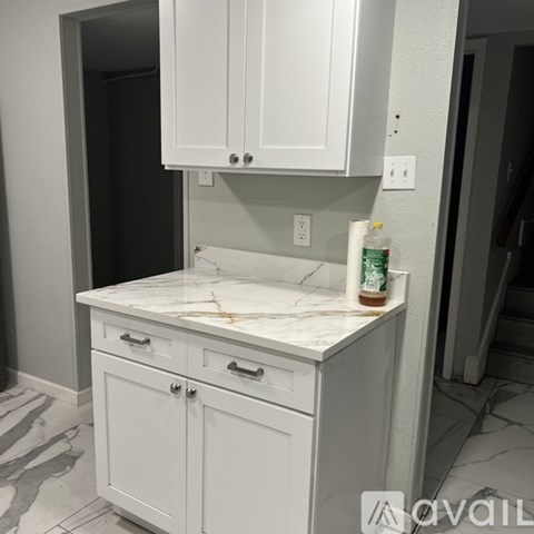 A white kitchen counter with a bottle of Coca-Cola on it.