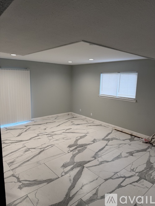A room with a marble floor and a window with blinds.