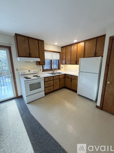 A kitchen with white appliances and wooden cabinets.