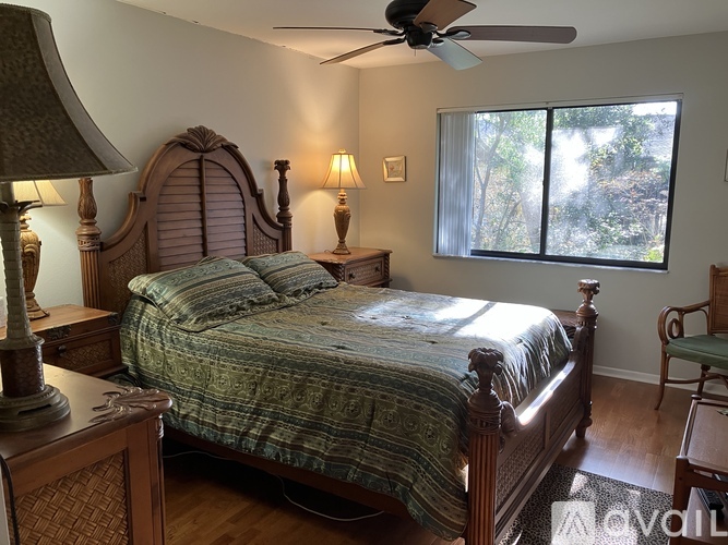 A bedroom with a bed, a chair, and a ceiling fan.