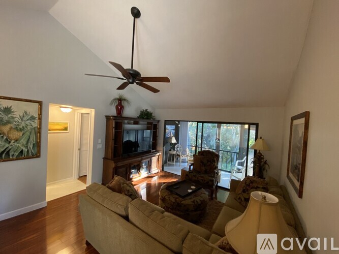 A living room with a beige couch and a ceiling fan.
