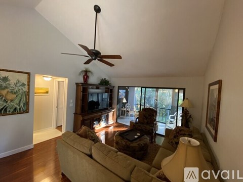 A living room with a beige couch and a ceiling fan.