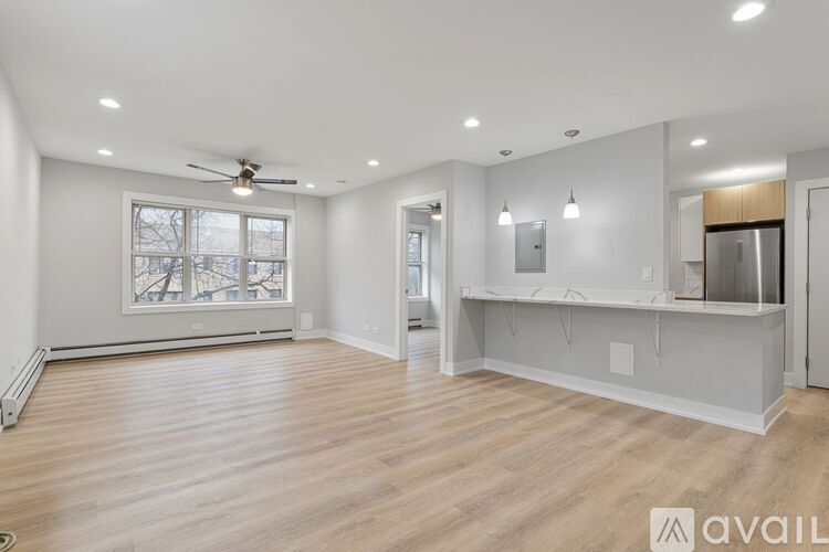 A spacious room with wooden flooring and a ceiling fan.